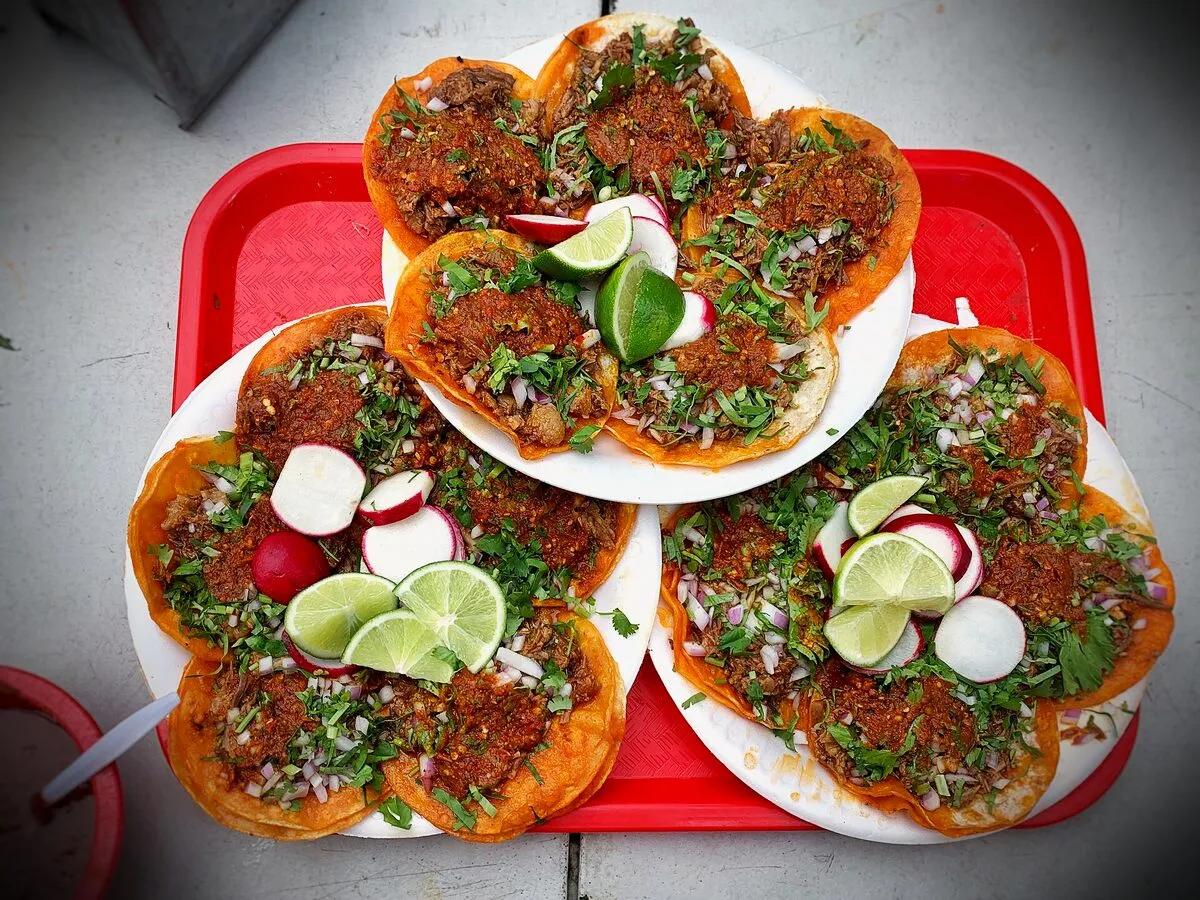 Tacos de birria recién servidos con cebolla, cilantro y limón